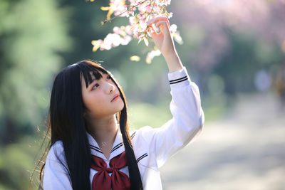 Portrait of young woman standing against blurred background