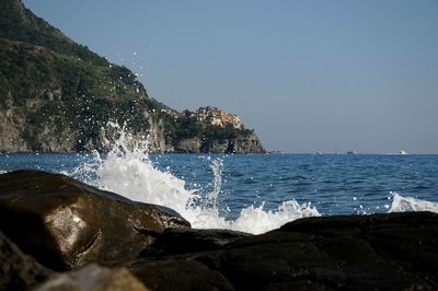 Sea waves splashing on rocks against clear sky