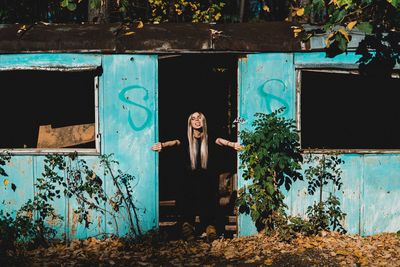 Portrait of young woman standing on abandoned house