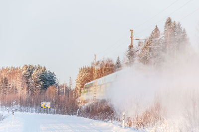 Train by trees against clear sky during winter