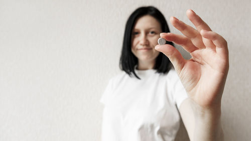 Portrait of woman holding hands against wall