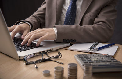 Midsection of man using laptop on table