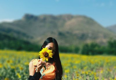 Woman holding yellow flower on field