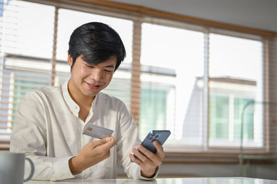 Young woman using mobile phone while sitting at home