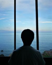 Rear view of man looking at sea against sky