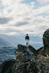 Rear view of man standing on mountain against sky