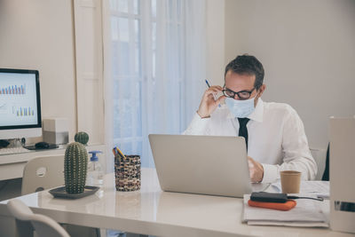 Business man working with laptop sitting at the desk. male works at computer communicate online 