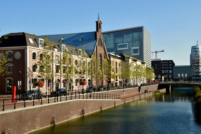 Canal by buildings against clear blue sky