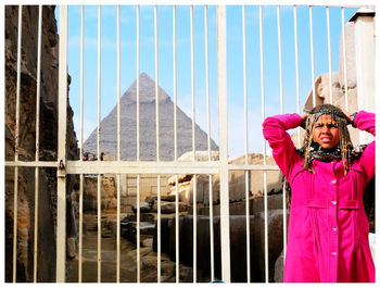 Portrait of young woman standing against building