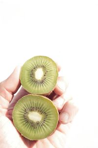 Close-up of hand holding fruit over white background