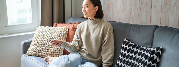 Young woman using laptop while sitting on sofa at home