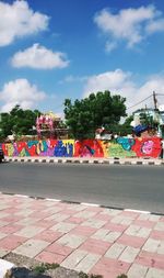 Group of people on street against cloudy sky