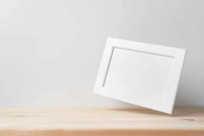 Low angle view of white paper on table against wall