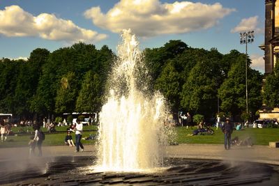 People enjoying at fountain against sky