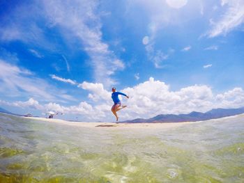 Full length of woman jumping on shore at beach