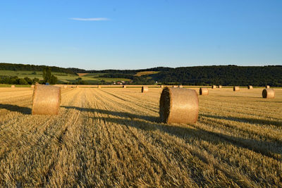 Hay bales on field against clear sky