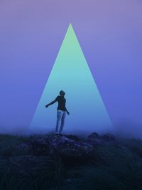 Man standing on rock against sky