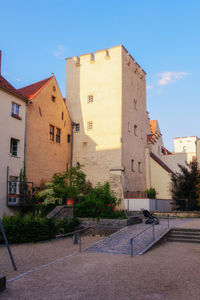 Buildings by street against blue sky