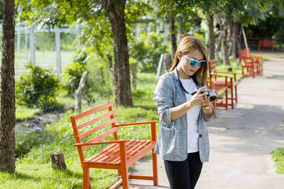 Young woman using mobile phone while standing in park