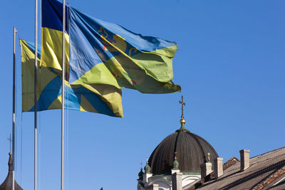 Low angle view of flags against clear blue sky