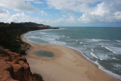 View of calm beach against cloudy sky