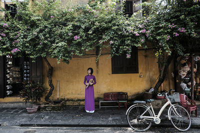 Woman holding bouquet while standing on footpath