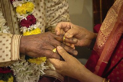 Midsection of bride and groom exchanging rings during wedding ceremony