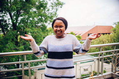 Portrait of smiling woman standing by railing