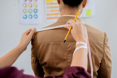 Cropped hands of fashion designer measuring woman at studio