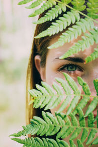 Cropped portrait of woman seen through fern leaves