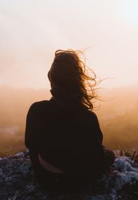 Rear view of woman against sky during sunset