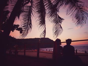 Silhouette people on beach against sky during sunset