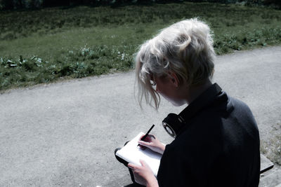 Rear view of man using mobile phone on road