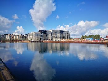 Reflection of buildings in lake against blue sky