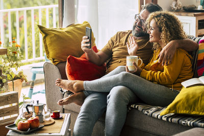 Smiling couple on video call while sitting on sofa