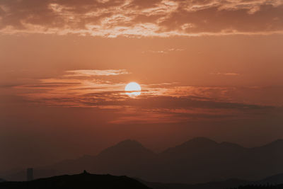 Scenic view of silhouette mountains against romantic sky at sunset