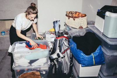 Woman sorting out clothes in containers during relocation of house