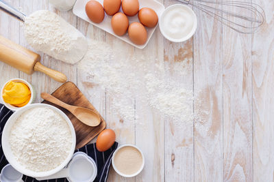 Homemade dough recipe eggs, flour, milk, sugar on white wooden table. view from above