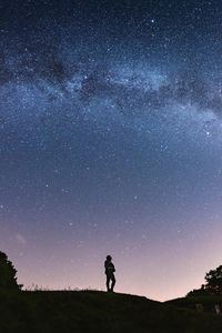 Silhouette man standing on field against sky at night