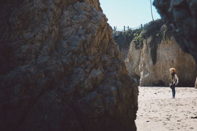 Mid distance view of mid adult woman at beach seen through rocks