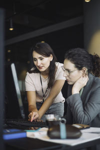 Young woman using mobile phone while sitting on table