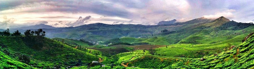 Panoramic view of green mountains against cloudy sky