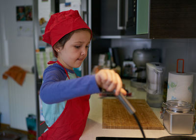 Girl in a red chef's hat is in the kitchen of her house