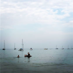 Sailboats in sea against sky