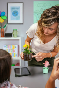 Female teacher showing pansy plant roots to her students in ecology classroom