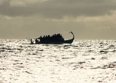 Silhouette people in sea against sky