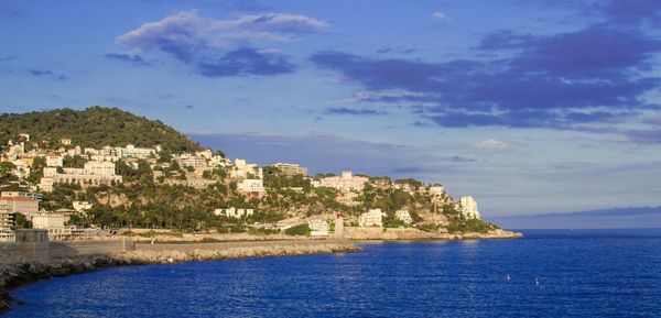 Scenic view of sea by buildings against sky