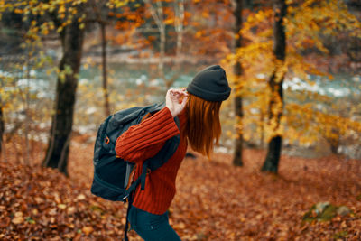 Side view of man with umbrella walking on autumn leaves