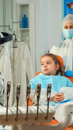 Girl sitting at hospital with parent at background