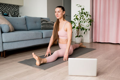 Online yoga classes. woman doing virtual yoga from laptop at home for develop core strength
